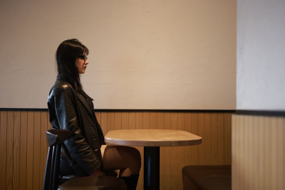 A woman in a black leather jacket sitting at a cafe table